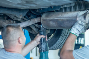 Mechaniker führt Servicemaßnahmen am Auspuff durch