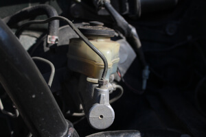 Nahaufnahme eines defekten Hauptbremszylinders in einem Auto