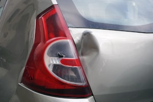 Nahaufnahme eines Lackschadens und einer Delle an der Heckklappe eines Autos