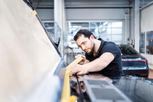 Fachmann bereitet das Auto vor, indem er es vor dem Lackieren der Motorhaube abklebt