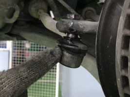 Mechaniker zeigt auf einen gebrochenen Spurstangenkopf