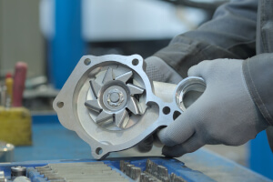 Fachmann tauscht die Wasserpumpe in der Werkstatt aus